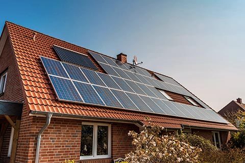 Hus med røde tagsten og solcellepaneler på taget